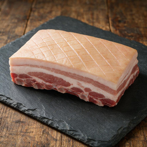 Belly Pork Bone In - raw British pork belly joint with diamond scored rind on slate, Staffordshire Meats